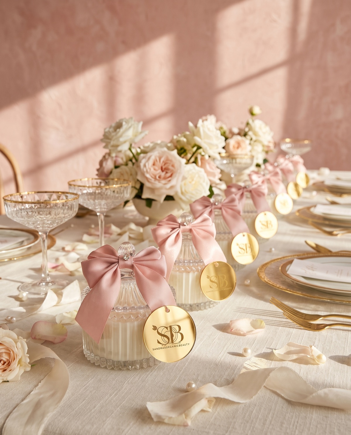 Blush bow jar candles with gold mirror tags in a row along a wedding table
